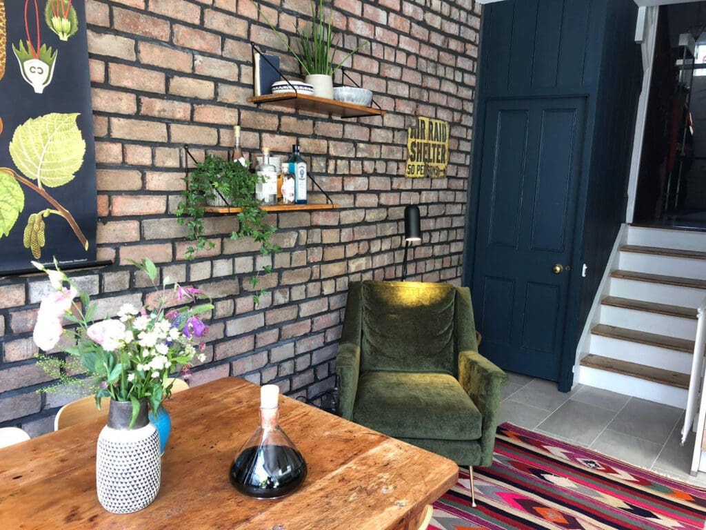 Cosy converted room with brick feature wall, armchair and stairs leading upward